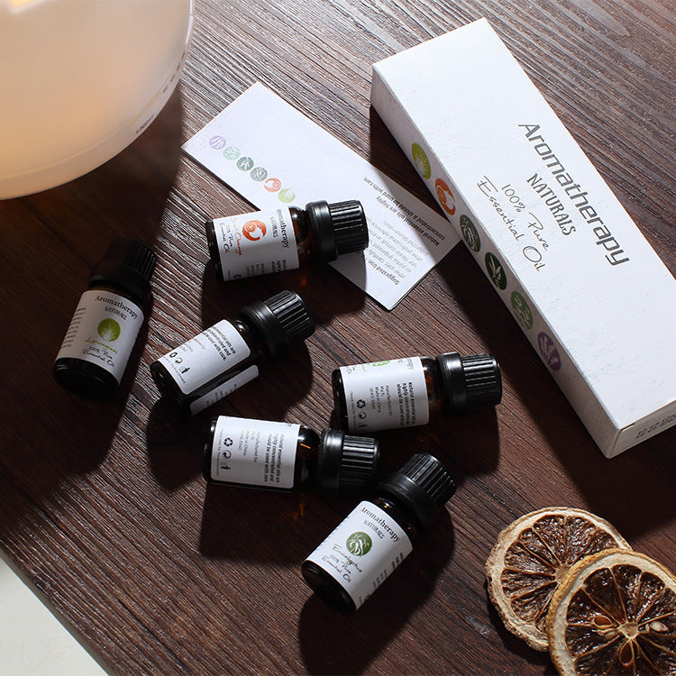 Collection of essential oil bottles on a wooden surface with a box labeled 'Aromatherapy Naturals'.