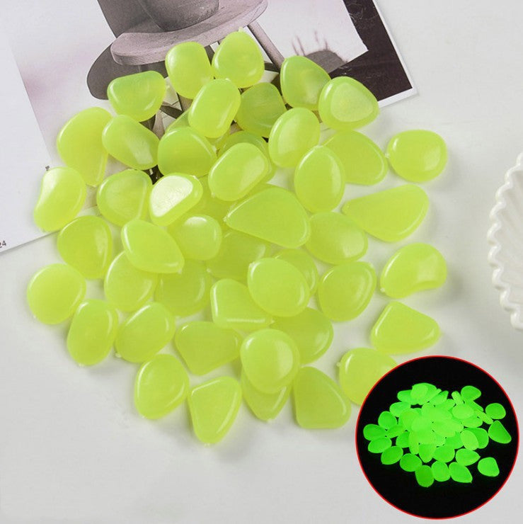 Green glowing stones on a white surface with a close-up inset showing their glow in the dark property.