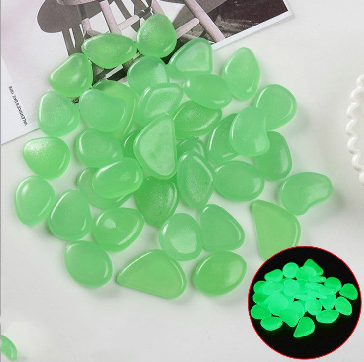 Green glowing stones on a white surface with a close-up inset showing their glow in the dark property.