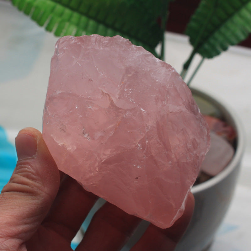 Hand holding a pink crystal rock with a blurred background