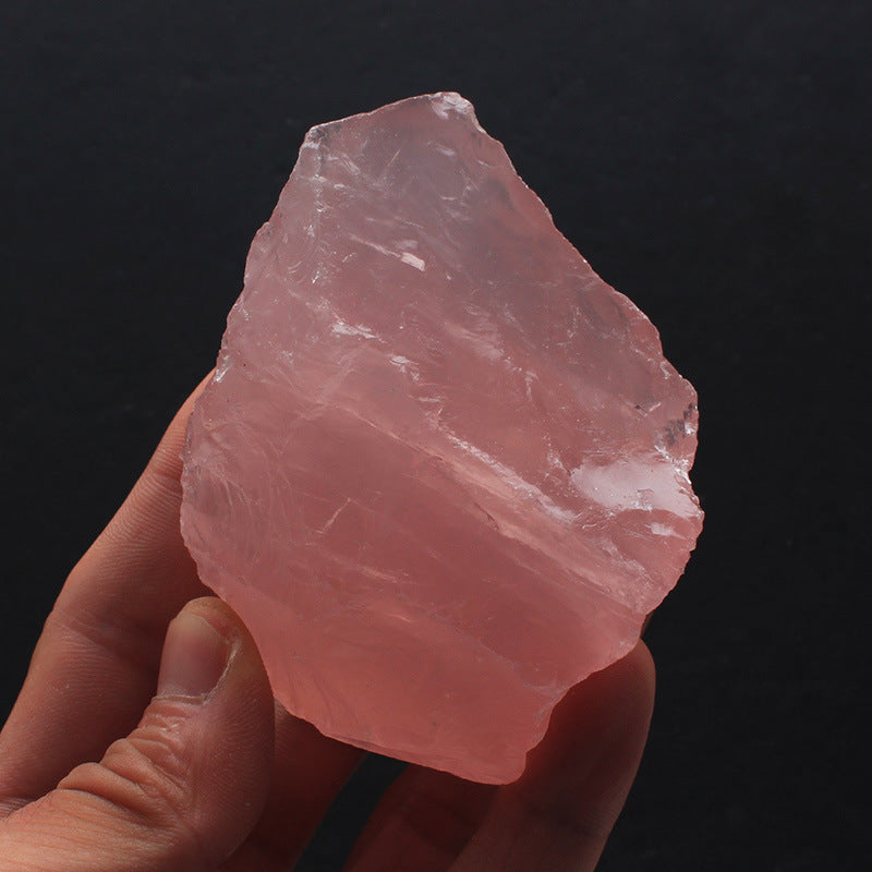 Hand holding a pink crystal against a black background