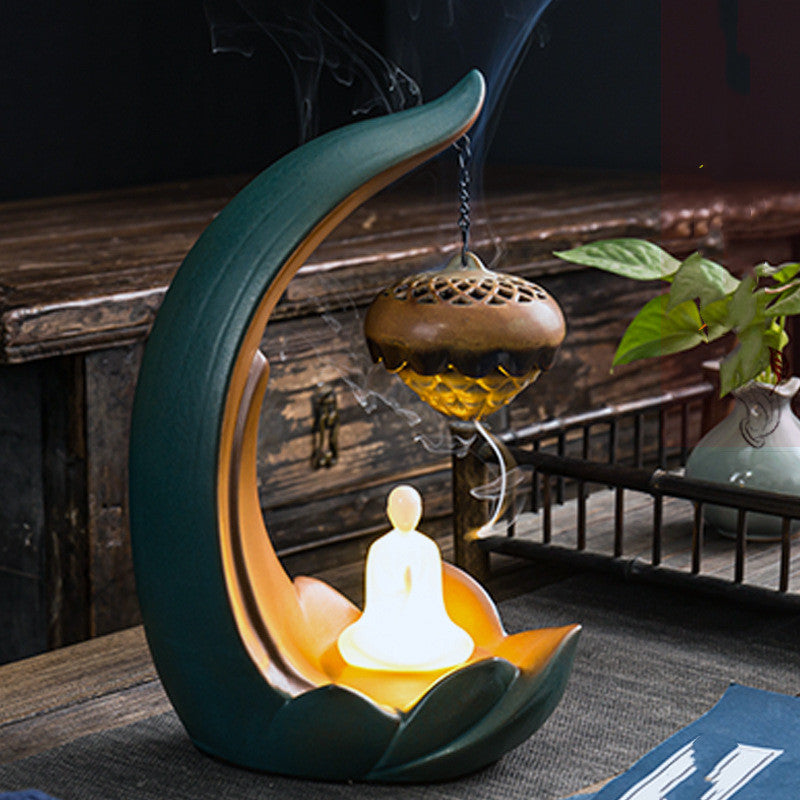 Decorative incense burner shaped like a crescent moon with a candle inside, on a wooden surface.