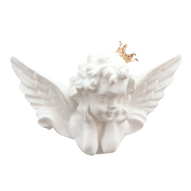 White angel statue with wings and a gold crown on a white background