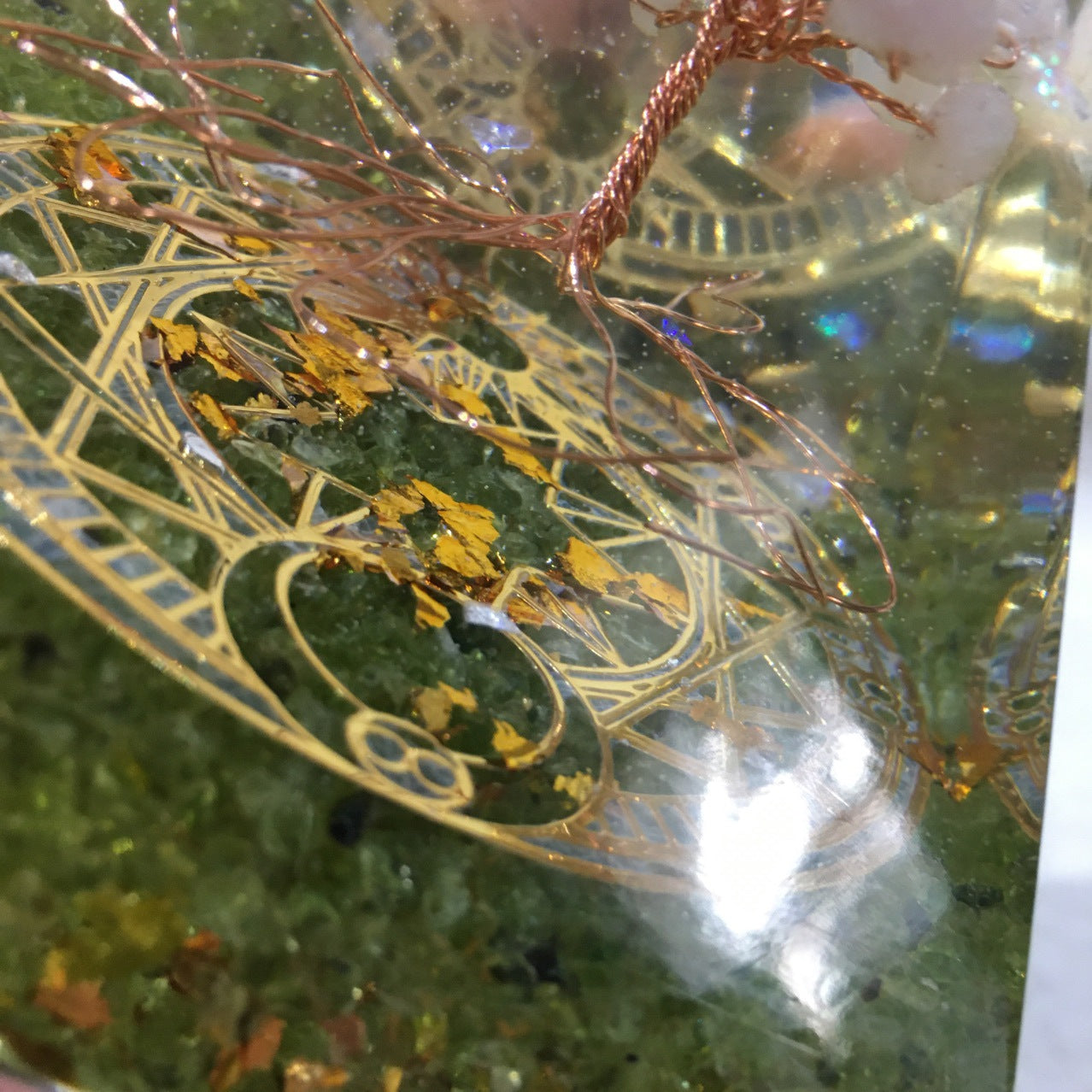 Close-up of a decorative item with gold and green patterns on a textured surface.