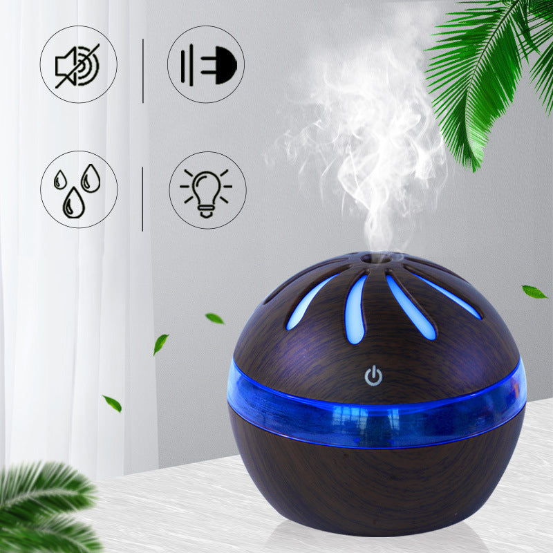 Aromatherapy diffuser with blue lights on a white surface with green leaves in the background