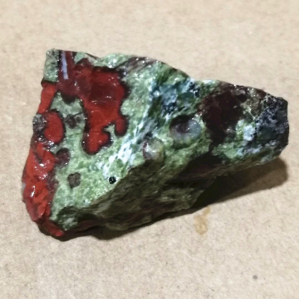 Mineral sample with red and green colors on a beige background