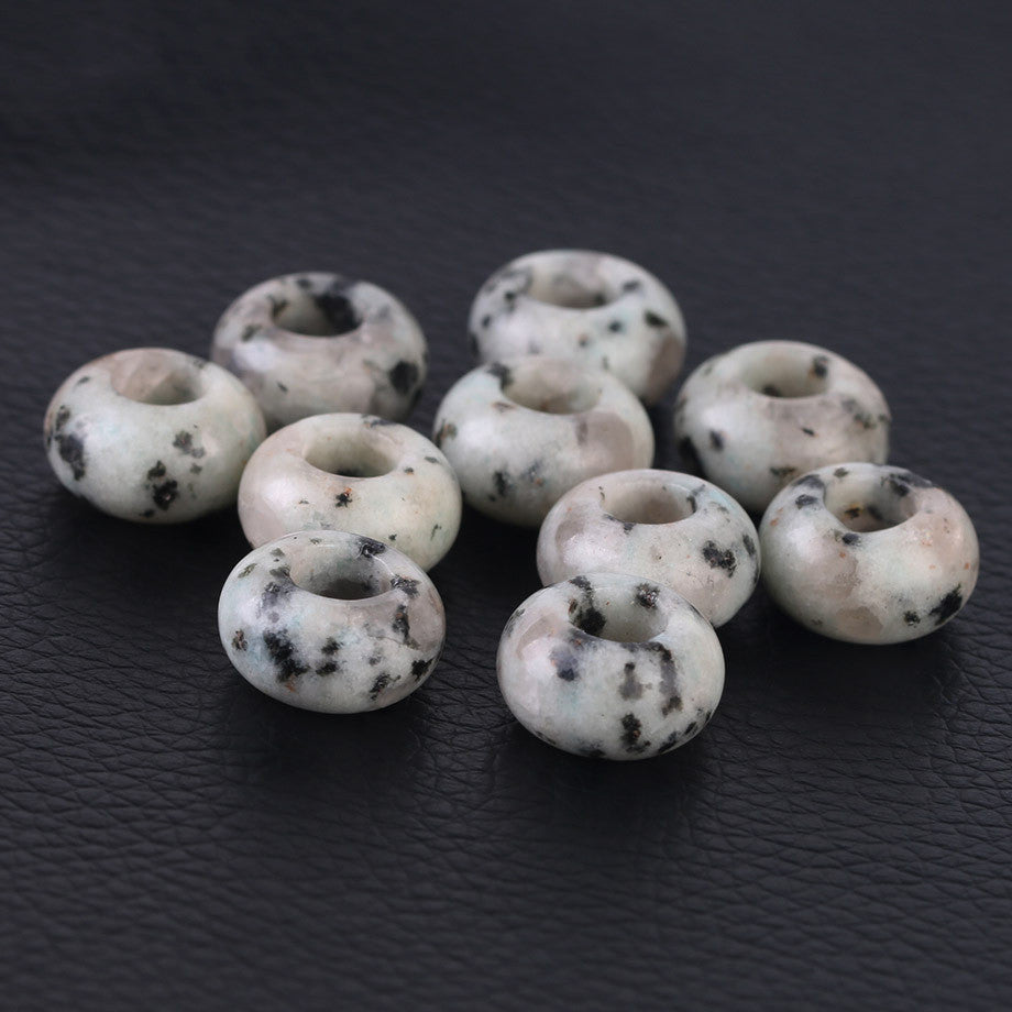White beads with black spots on a dark textured surface