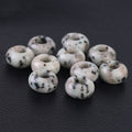 White beads with black spots on a dark textured surface