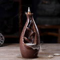 Brown ceramic incense burner with smoke on a wooden surface