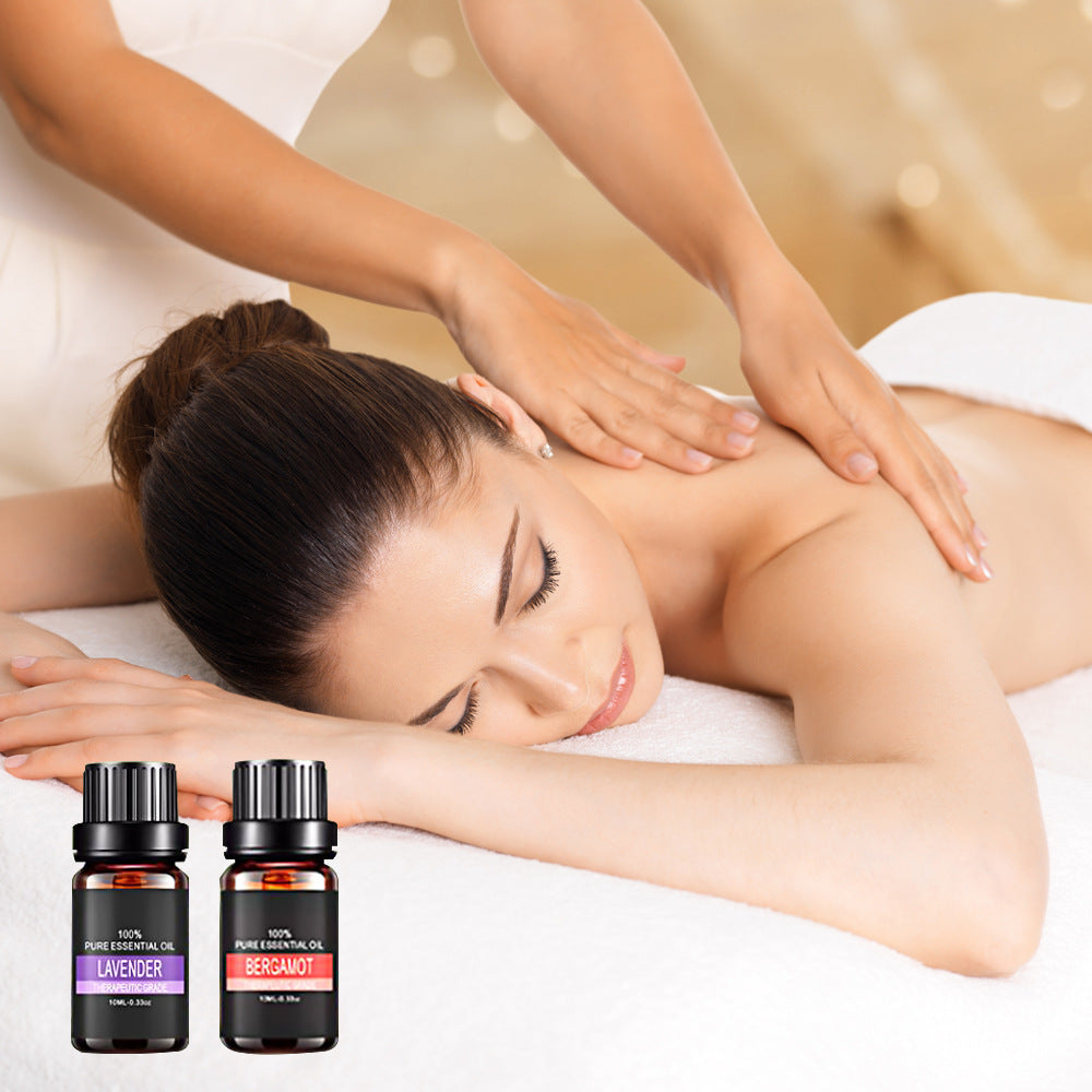Woman receiving a massage with essential oil bottles displayed in the foreground.