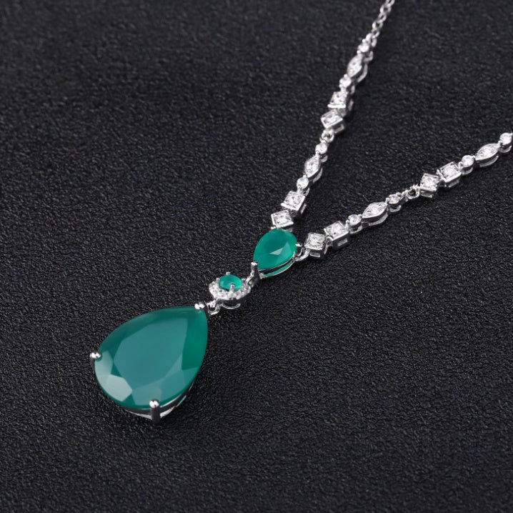 Necklace with a green teardrop pendant and diamond-like stones on a black background