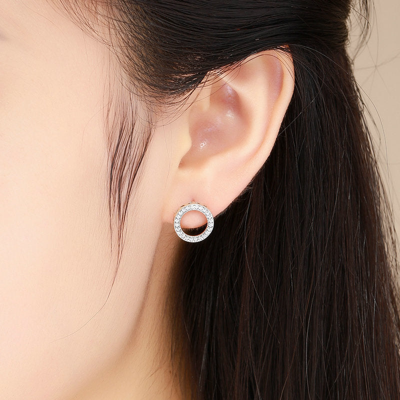 Close-up of an ear wearing a silver hoop earring with a blurred background
