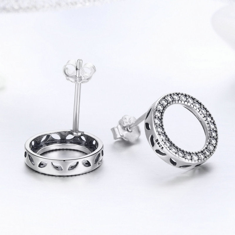 Silver earrings with circular design and embedded stones on a white background