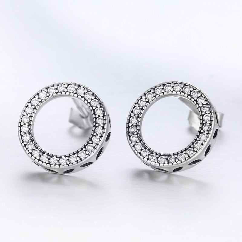 Pair of silver hoop earrings with clear gemstones on a light gray background