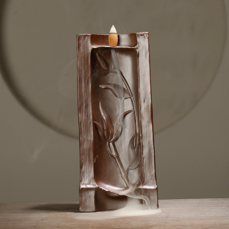 Decorative incense burner with leaf design on a neutral background
