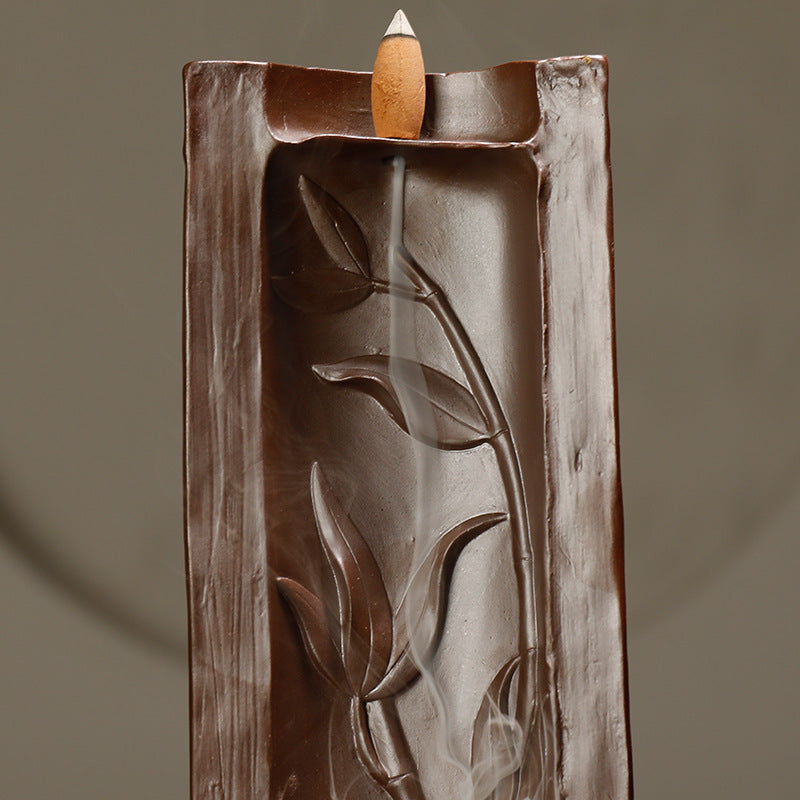 Decorative incense burner with leaf design on a brown background