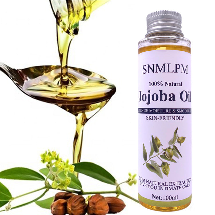 Bottle of SNMLPM Jojoba Oil with a spoonful of oil and jojoba beans on a white background