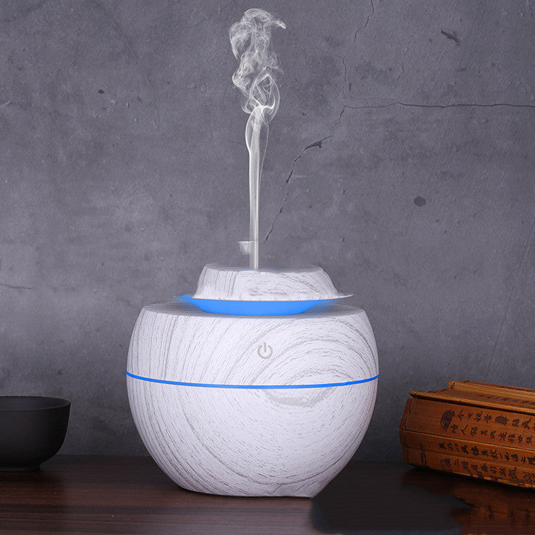 White marble-patterned diffuser with blue accents on a dark surface and gray background