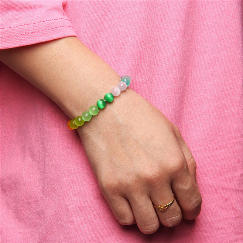 Colorful beaded bracelet on a wrist against a pink background