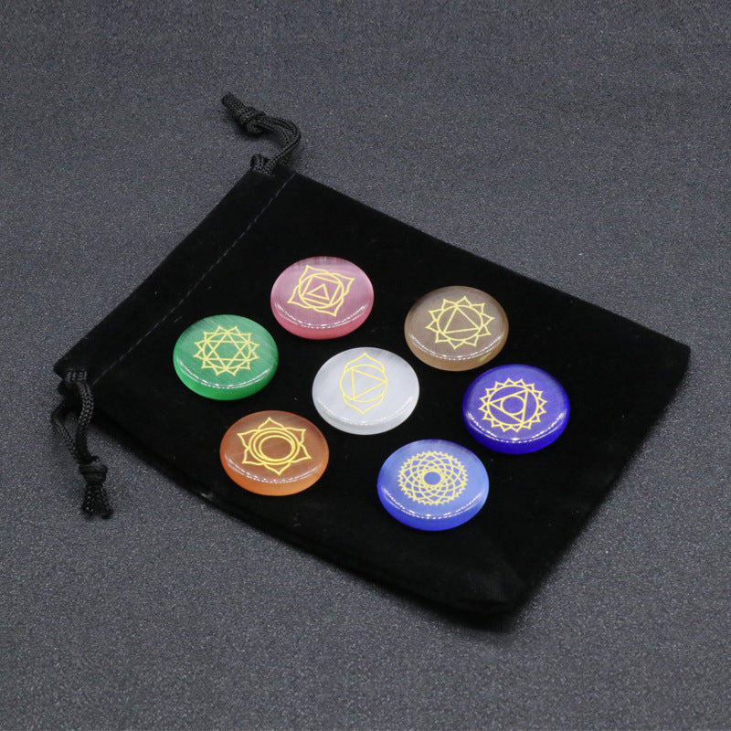 Set of colorful stones with symbols on a black drawstring bag against a dark background