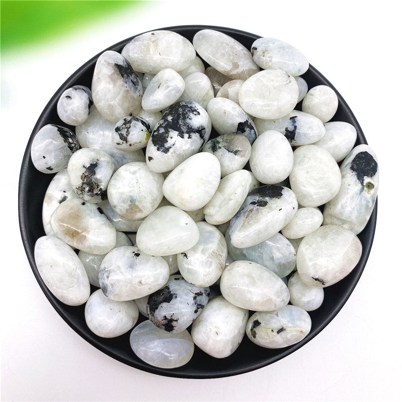 White stones with black spots in a black bowl on a white background