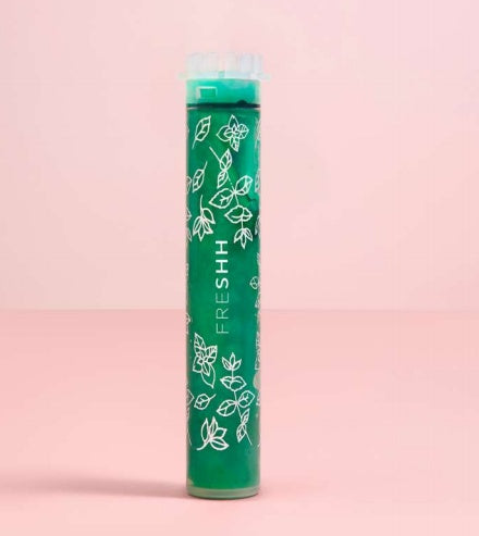 Green cylindrical product with 'FRESHH' branding on a pink background