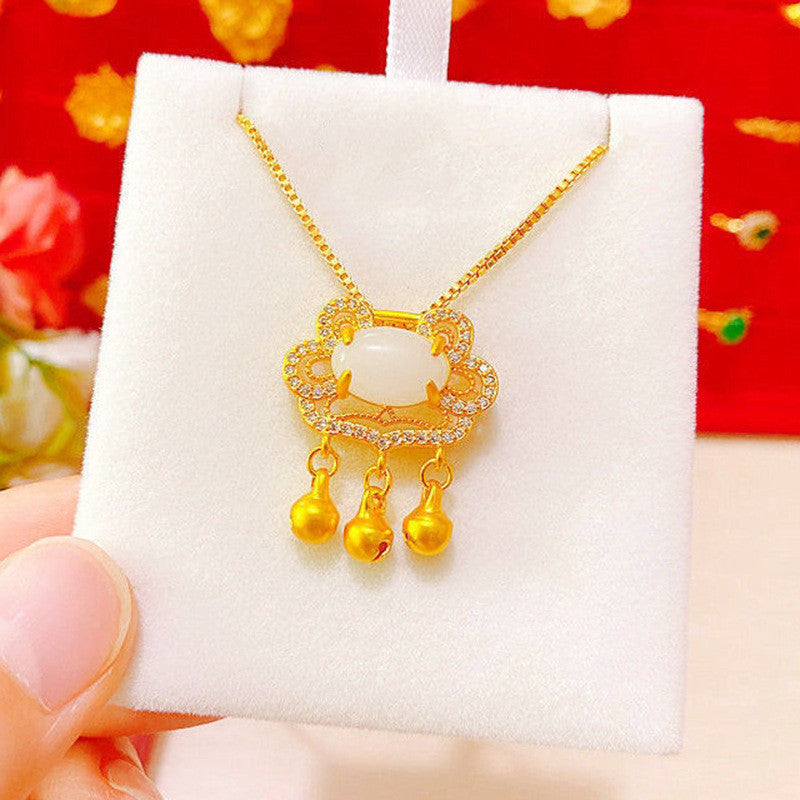 Gold necklace with pendant on a white card against a red floral background