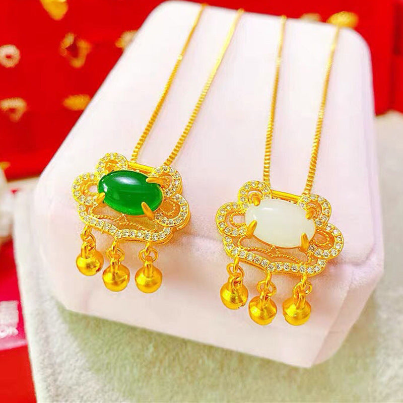 Two gold necklaces with green and white gemstones on a white stand with a red background.