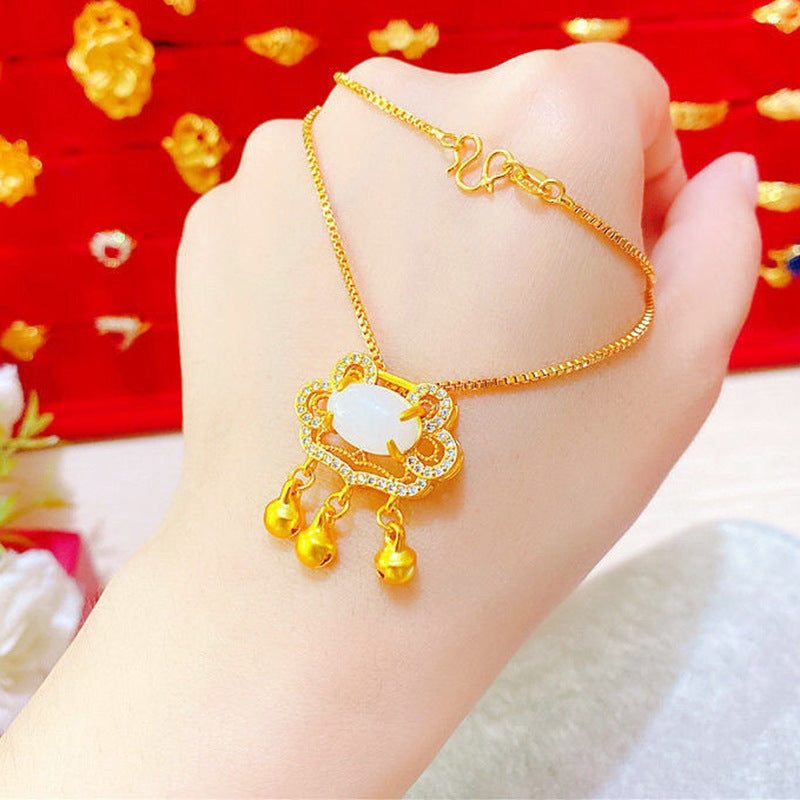 Gold bracelet with a white stone and gold beads on a hand against a red background
