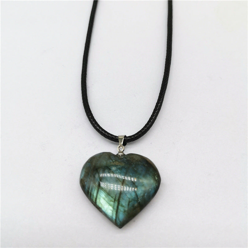 Heart-shaped labradorite pendant on a black cord against a white background