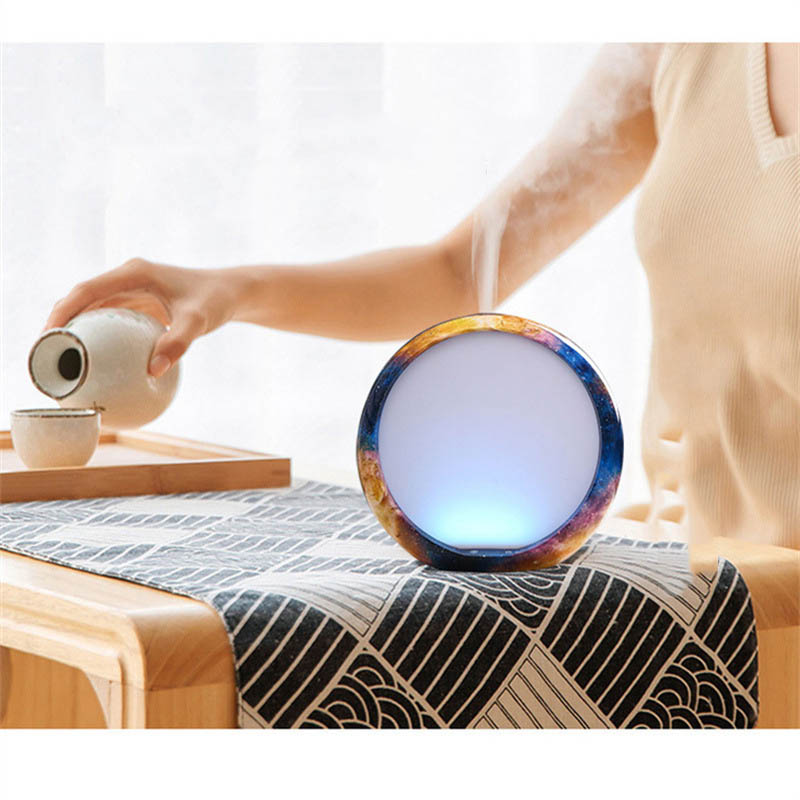 Person pouring tea into a colorful round lamp on a table.