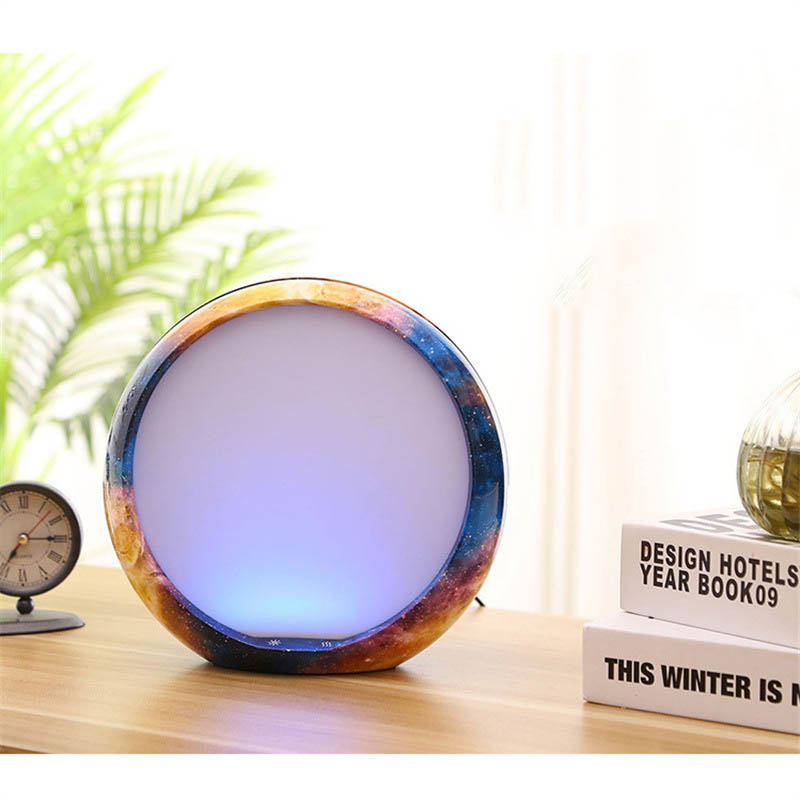 Round multicolored lamp on a wooden surface with books and a clock in the background