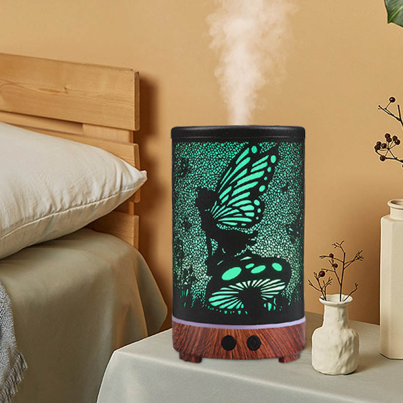 Decorative diffuser with butterfly design on a nightstand next to a bed.