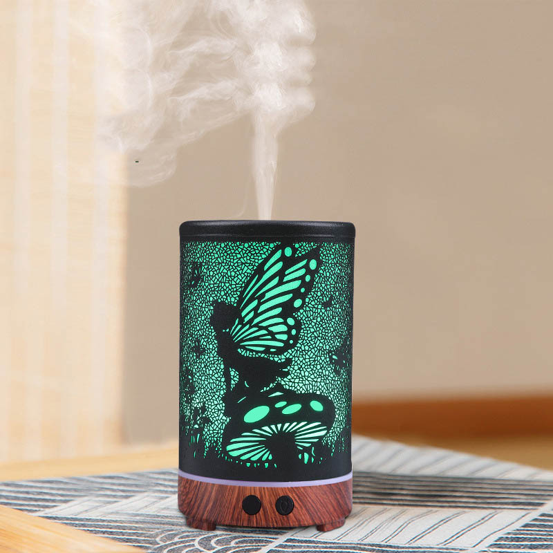 Decorative diffuser with butterfly design emitting mist on a striped fabric surface.
