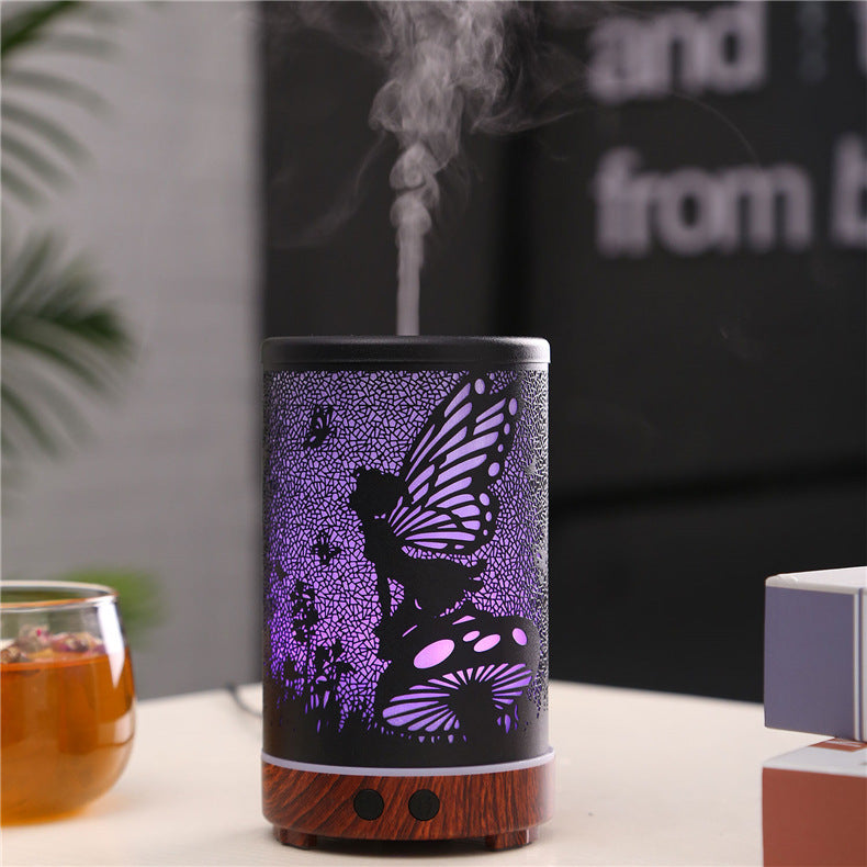 Decorative diffuser with butterfly design emitting mist on a blurred background