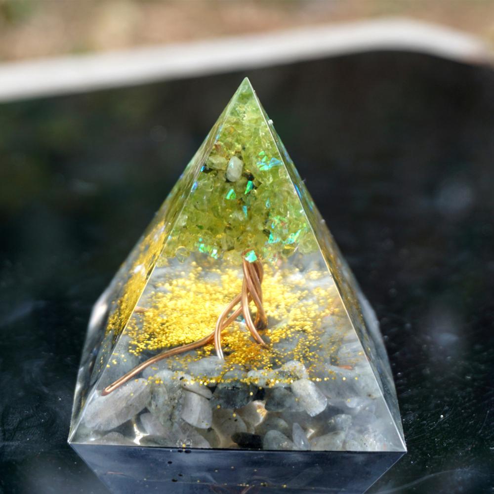 Crystal pyramid with embedded stones and gold flakes on a reflective surface