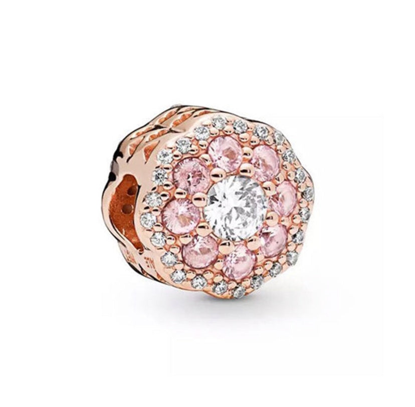 Jewelry charm with pink gemstones and rose gold accents on a white background