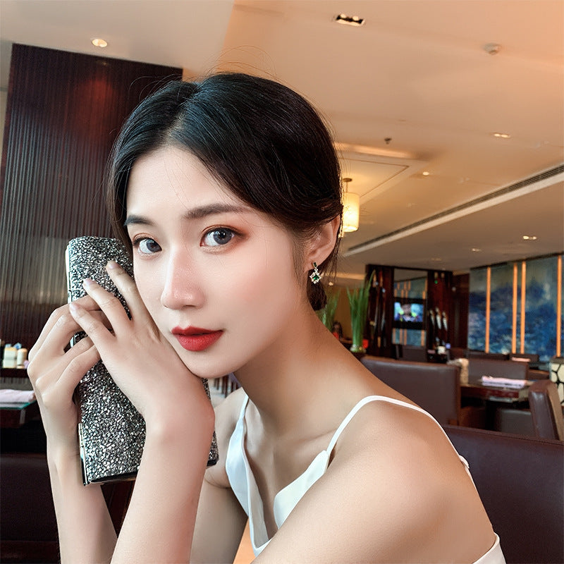 Woman holding a sparkling handbag in an indoor setting