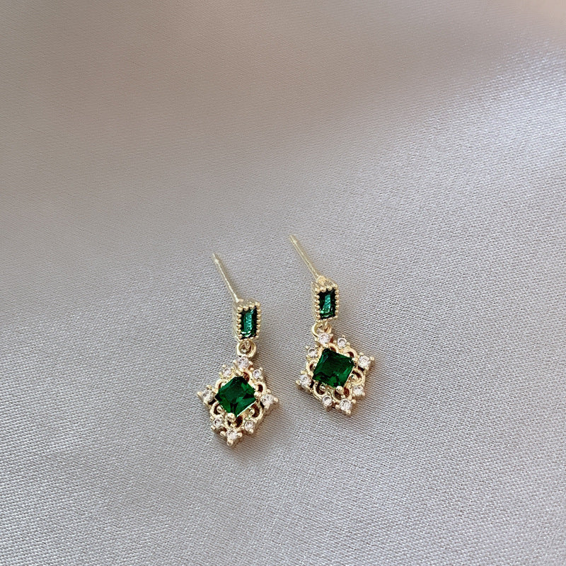 Pair of emerald green gemstone earrings on a light gray background