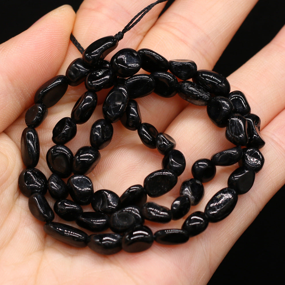 Black stone beads on a string held in a hand against a dark background