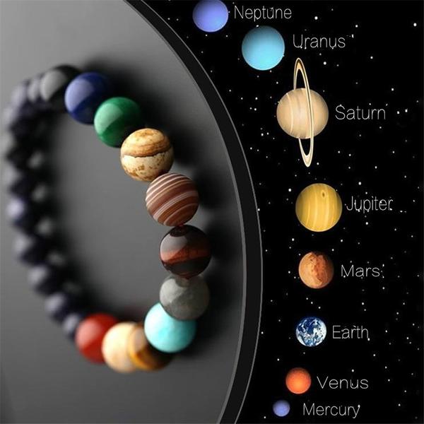 Bracelet with colorful beads resembling planets next to an illustration of the solar system on a dark background.