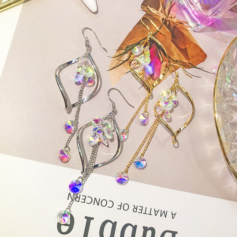 Pair of dangling earrings with colorful crystals on a light background