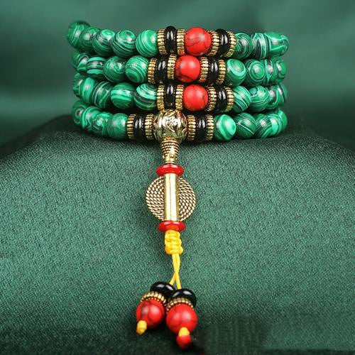 Multicolored beaded bracelet with gold accents on a green fabric background