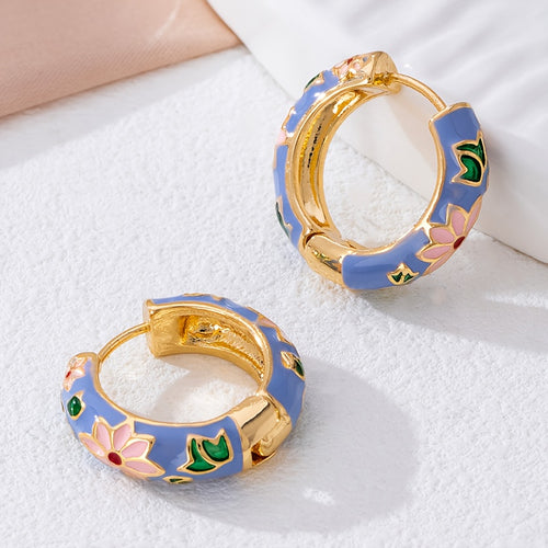 Pair of gold hoop earrings with blue and floral designs on a white surface