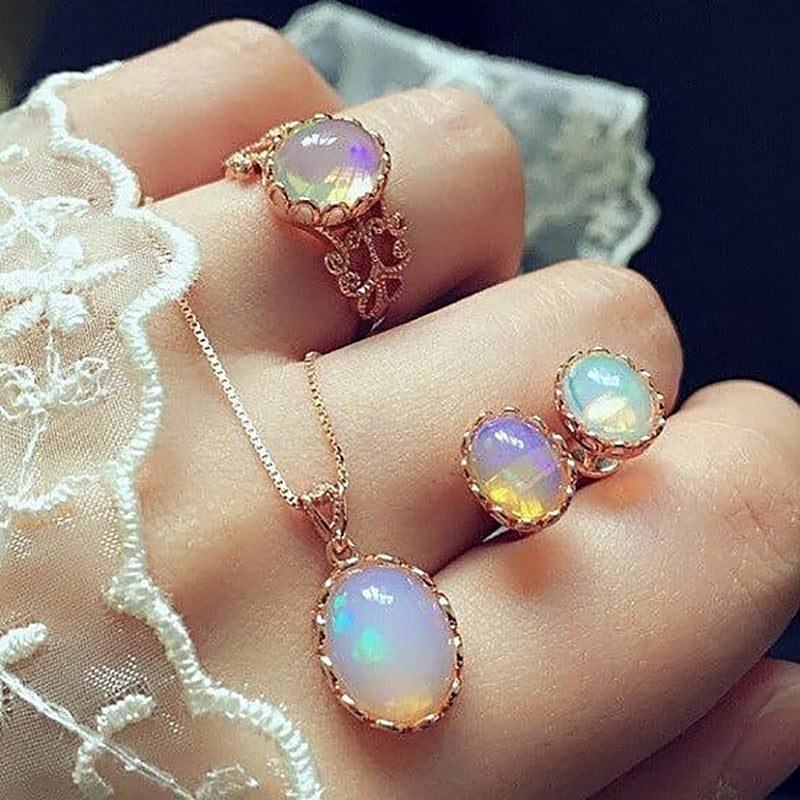 Rose gold jewelry set with opal stones on a hand wearing a lace glove.