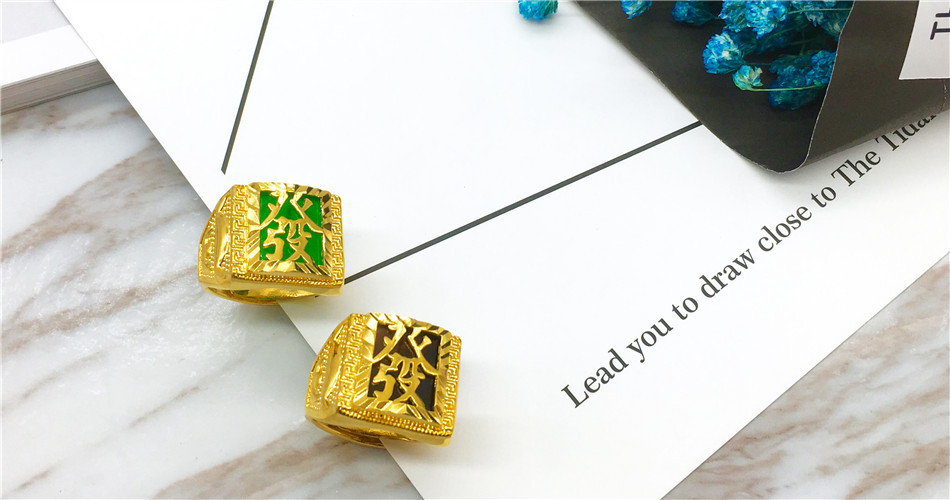 Gold square-shaped items with green and black designs on a marble surface.