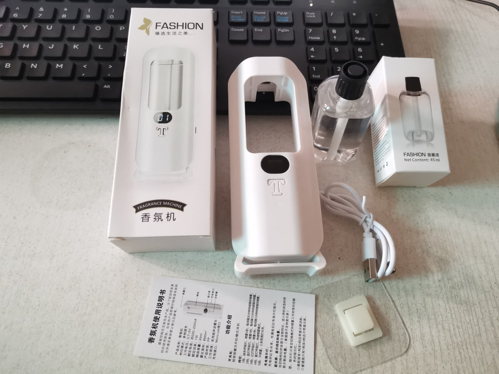Personal fragrance machine with packaging and accessories on a desk