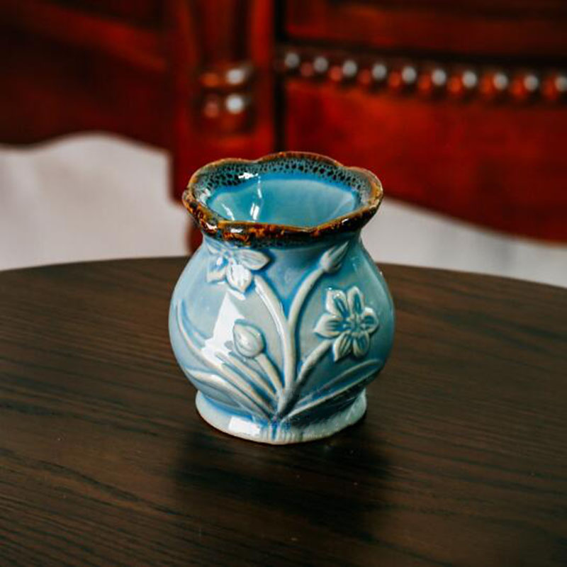 Blue ceramic vase with floral patterns on a wooden surface