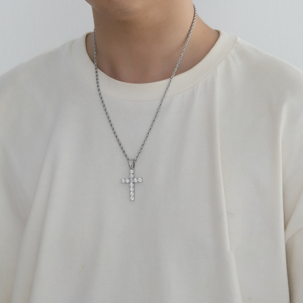 Silver cross necklace on a person wearing a white shirt against a plain background