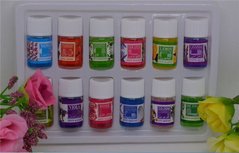 Set of small bottles with colorful labels on a white tray, surrounded by flowers.
